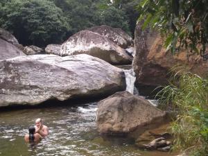dos personas en el agua cerca de una cascada en Tranquilidade e diversão, en Mangaratiba