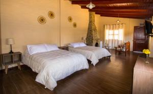 1 dormitorio con 2 camas y chimenea en Tuki Llajta - Pueblo bonito Lodge, en Huancayo