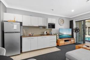 a kitchen with white cabinets and a tv in it at Eden by the Bay in Hervey Bay