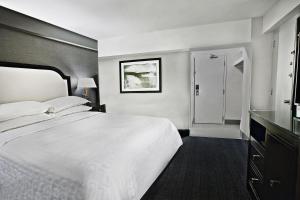 a bedroom with a large white bed and a bathroom at Sheraton Fallsview Hotel in Niagara Falls