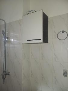uma casa de banho com um chuveiro e um armário branco em KESEWAA's APARTMENT em Acra