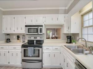 una cucina con armadietti bianchi, piano cottura e forno a microonde di Beacon House, Central to Augusta ad Augusta