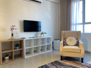 a living room with a tv and a chair at The Cotton Bleu Homestay in Kuala Terengganu