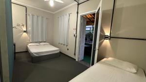 mały pokój z 2 łóżkami i lustrem w obiekcie Suíte nº 11 - Praia das Pitangueiras w mieście Guarujá