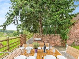 een houten tafel met een fles wijn en een boom bij The Horse Gin in Marldon