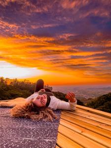 Pousada Caminho dos Canyons في برايا جراندي: امرأة مستلقية على الأرض مع غروب الشمس في الخلفية