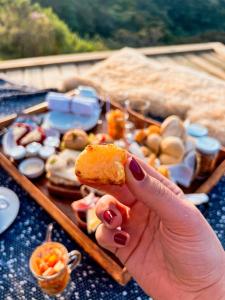 a hand holding a piece of bread next to a tray of food at Pousada Caminho dos Canyons in Praia Grande