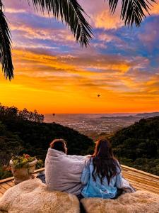 Zwei Leute sitzen auf einem Felsen und beobachten den Sonnenuntergang. in der Unterkunft Pousada Caminho dos Canyons in Praia Grande