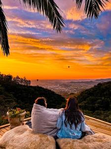 two people sitting on a rock watching the sunset at Pousada Caminho dos Canyons in Praia Grande