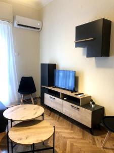 een woonkamer met 2 tafels en een tv bij athens oasis in Athene