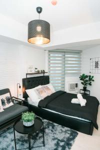 a bedroom with a large black bed and a chair at Resort Condo Unit with Stunning View - Azure North in Lagundi +23 photos