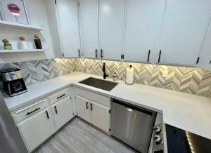 uma cozinha com armários brancos e um lavatório em MCM Condo Downtown Palm Springs em Palm Springs