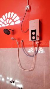 um chuveiro na casa de banho com uma parede vermelha em MNOOR HOMESTAY em Marang