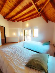 2 camas en una habitación con techos de madera en CABAÑAS BANDURRIAS en San Martín de los Andes