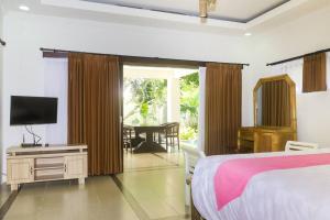 a bedroom with a bed and a flat screen tv at Dzawani Villa Kerobokan in Kerobokan