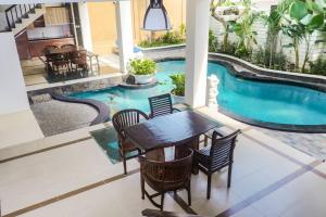 a patio with a table and chairs next to a swimming pool at Dzawani Villa Kerobokan in Kerobokan