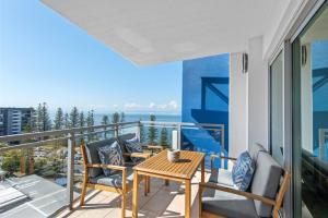 balcón con mesa, sillas y vistas al océano en Proximity Waterfront Apartments en Redcliffe