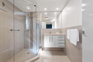a bathroom with a glass shower and a sink at Proximity Waterfront Apartments in Redcliffe