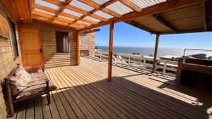 un porche de una casa con una silla y el océano en Cabaña Vista Bella, en Pelluhue