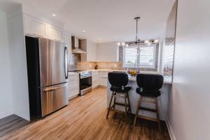 a kitchen with a stainless steel refrigerator and two bar stools at Khlozy Escape the ordinary. (Feonho) in Cornwall