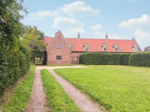una gran casa de ladrillo con un patio de hierba delante de ella en Ringland Cottage, en Attlebridge