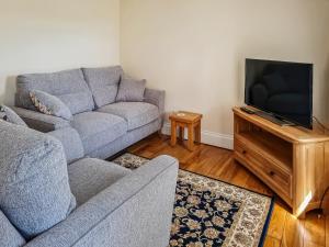 sala de estar con sofá y TV de pantalla plana en Carnlussack Cottage en Camborne