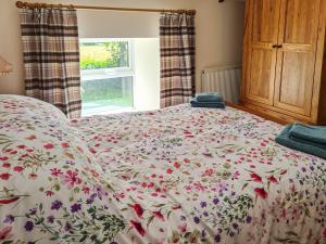 1 dormitorio con 1 cama con colcha de flores en Carnlussack Cottage en Camborne