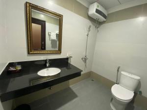 a bathroom with a toilet and a sink and a mirror at Khách sạn HOÀ BÌNH QUẢNG TRỊ in Ðông Hà