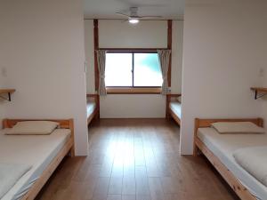 a room with two beds and a window at Guesthouse tonari in Inokuchi