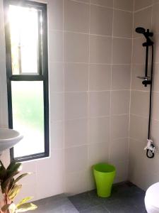 a bathroom with a green bucket next to a window at Camp Soteria Resort in San Agustin