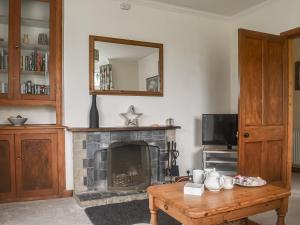 een woonkamer met een open haard en een houten tafel bij Oakleigh in Rathmell