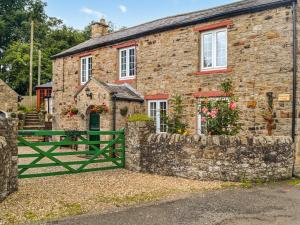 een stenen huis met een groene poort ervoor bij Stoneybeck-uk45044 in Greenhead