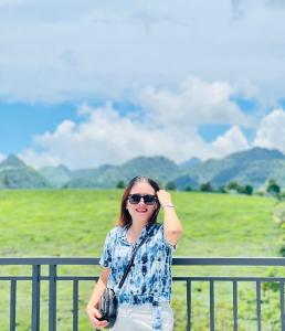 a woman standing in front of a fence at Đồi Chè Hotel in Mộc Châu