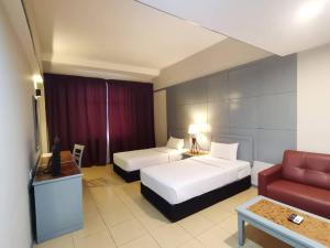 a hotel room with two beds and a couch at Grace Hotel Lahad Datu in Lahad Datu