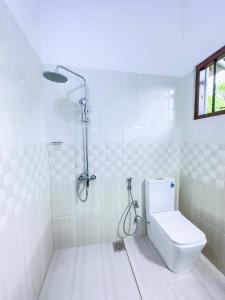 a white bathroom with a shower and a toilet at Sayuru Villa in Hikkaduwa