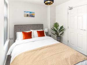 a white bedroom with a large bed with orange pillows at No,10 Apartments in Blackpool