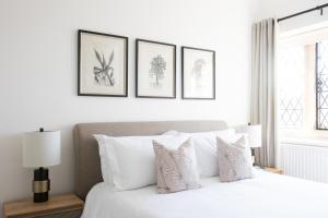 1 dormitorio con 1 cama blanca y 4 dibujos en la pared en Number 42 en Arundel