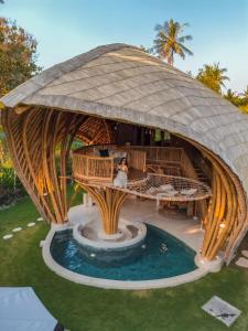 a person sitting in a gazebo next to a pool at Villa Tokay - Luxury Private Villas in Gili Islands