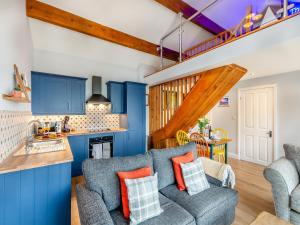 cocina y sala de estar con armarios azules y sofá en Farways Den, en Haworth