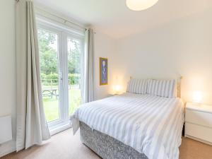 ein weißes Schlafzimmer mit einem Bett und einem Fenster in der Unterkunft Honey Hanger - W43106 in Bradworthy