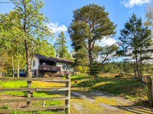 uma casa na floresta com uma cerca em Kintulloch em Insh