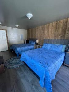 2 Betten in einem Schlafzimmer mit blauen Bettdecken darauf in der Unterkunft ParkWay Yellowstone Guest House Room #1 in Gardiner