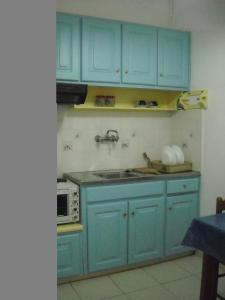 a kitchen with blue cabinets and a microwave at Maritsas Apartments in Roda