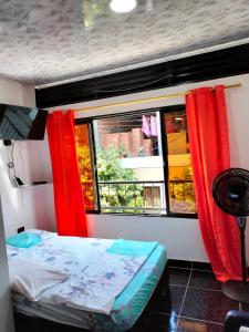 a bedroom with a bed and a window with red curtains at Apartamento, La paz in Puerto Triunfo
