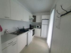 a white kitchen with a sink and a refrigerator at La Jenny Village Naturiste - chalet 4/6 personnes in Le Porge