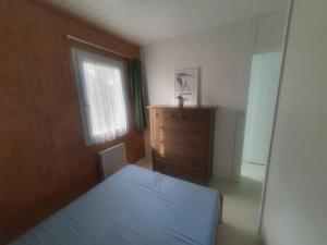 a bedroom with a bed and a dresser and a window at La Jenny Village Naturiste - chalet 4/6 personnes in Le Porge