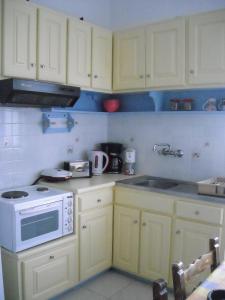 a kitchen with white cabinets and a white microwave at Maritsas Apartments in Roda