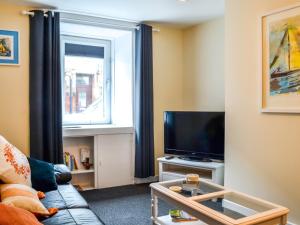 uma sala de estar com um sofá, uma televisão e uma janela em The Hydeaway em Whithorn