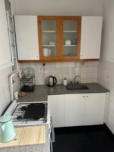 a kitchen with white cabinets and a stove and a sink at Santa Fe Apart in Buenos Aires