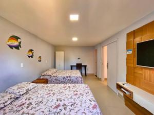 a hotel room with two beds and a flat screen tv at Apt FRENTE MAR MEAIPE COMPLETO in Guarapari